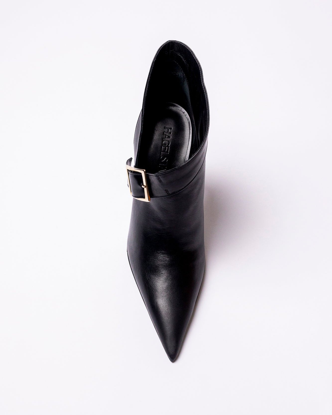 Black pointed-toe boot with a buckle on a white background