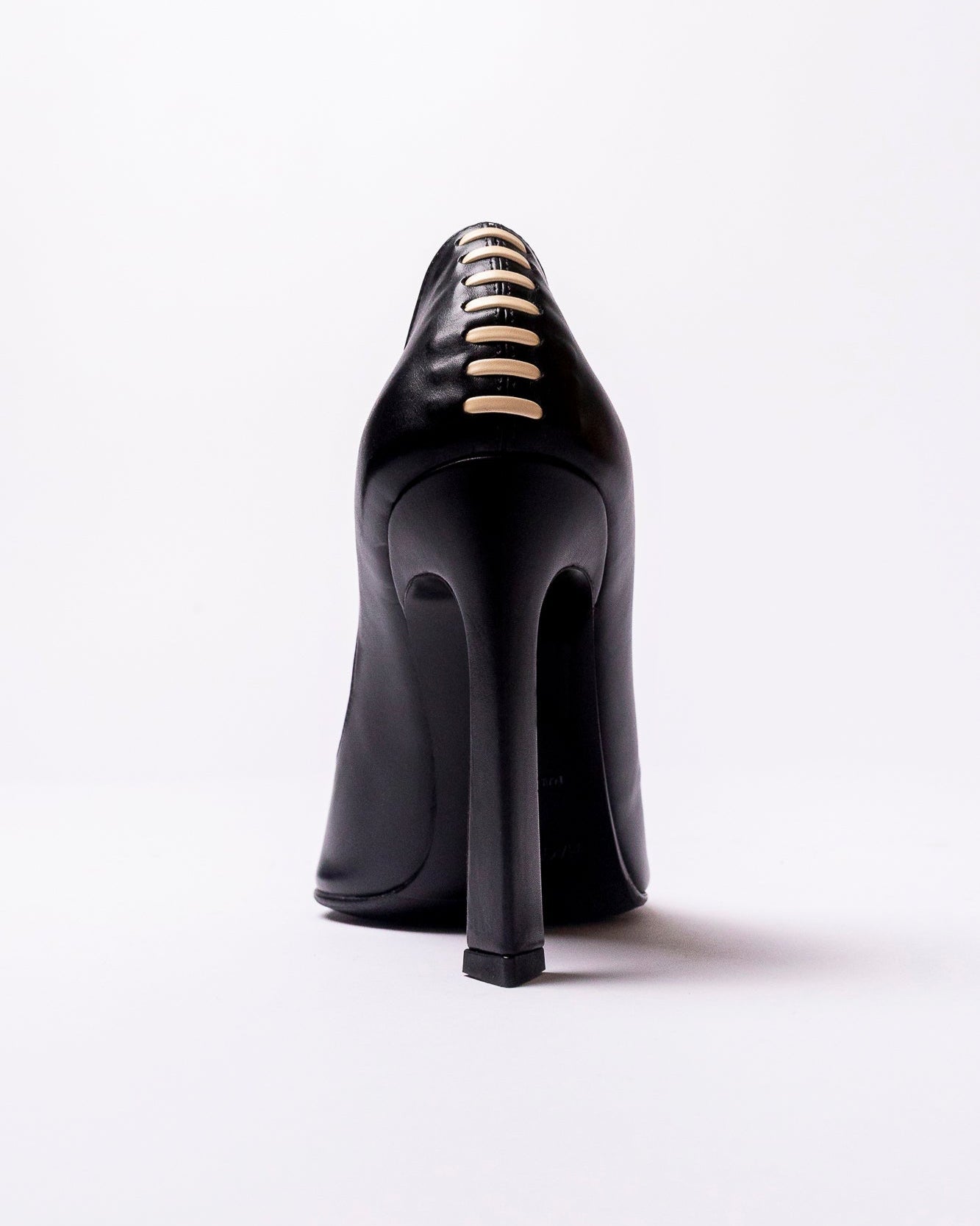 Black high-heeled shoe with gold accents on a white background